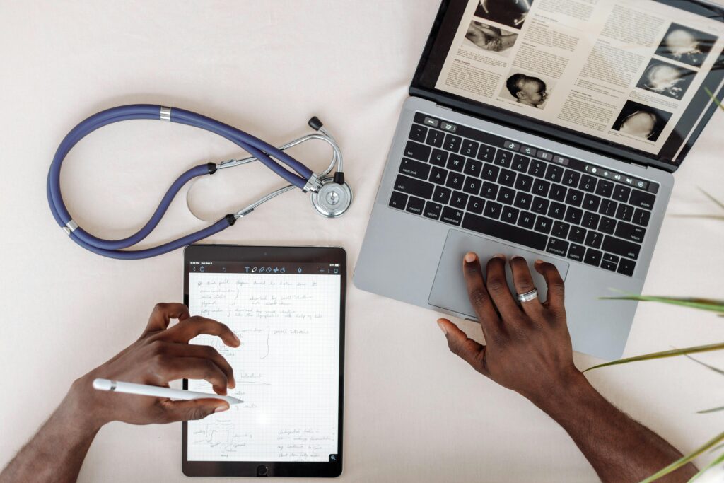 A medical expert doing research on a laptop and a tablet.